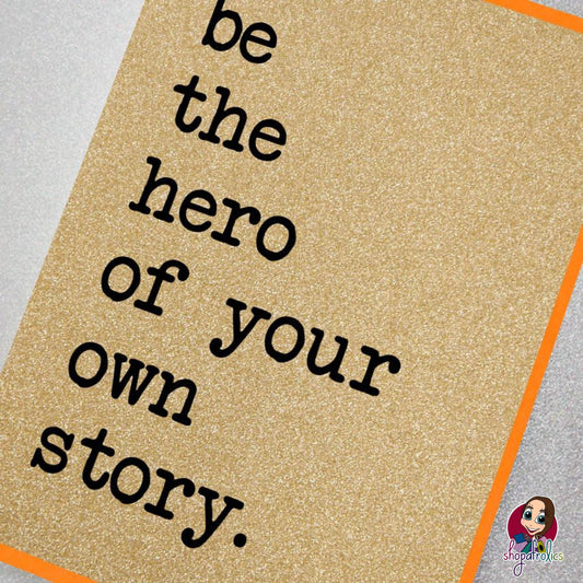 A fabulously sparkly gold glitter effect greeting card featuring the slogan: Be the hero of your own story.