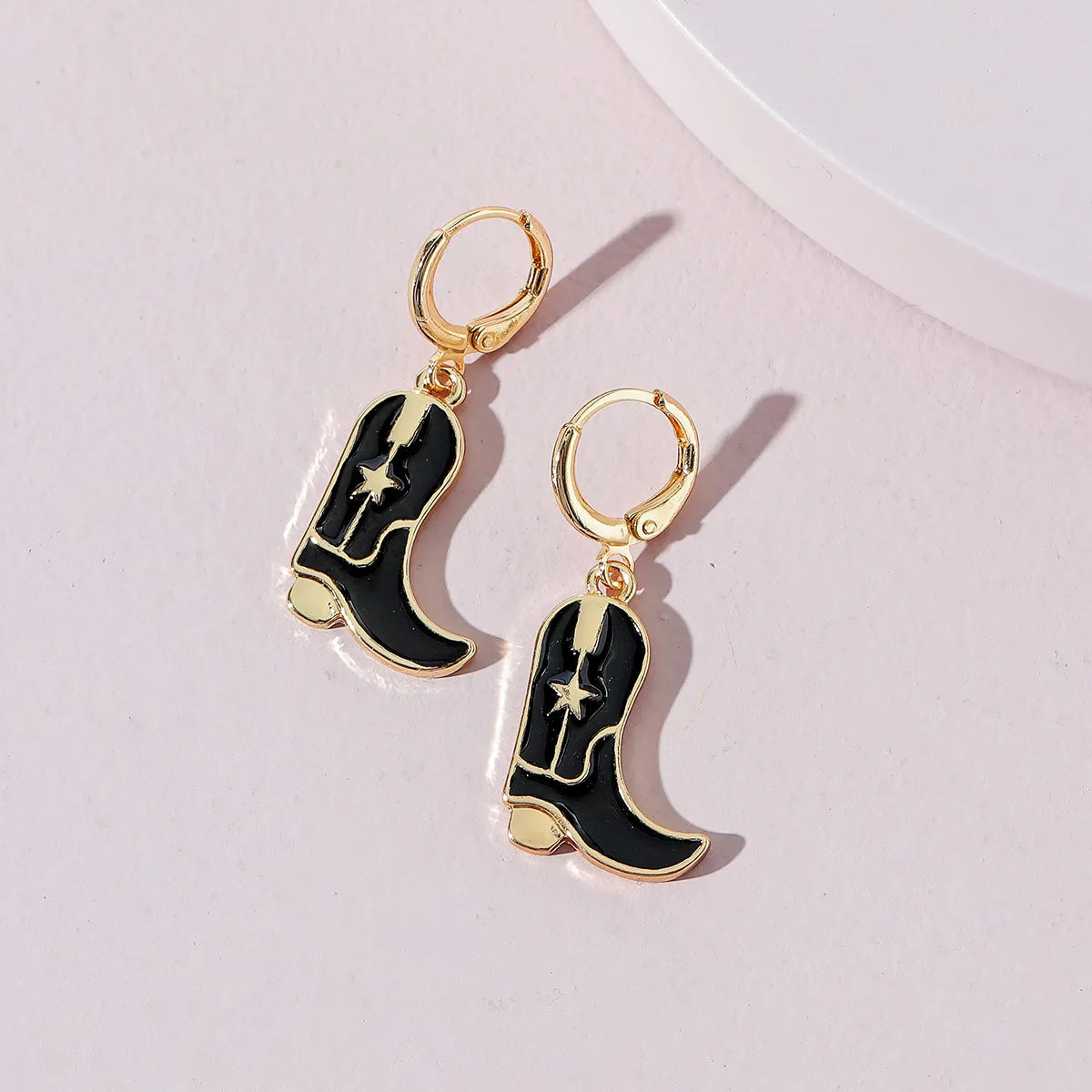 Flatlay of Black Cowboy Boots Gold Hoop Earrings