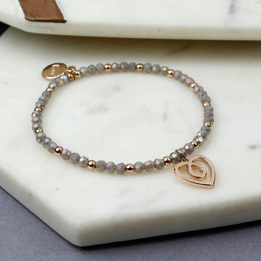 Grey pearlescent bead and rose gold bead stretch bracelet with a twist heart in a rose gold style finish.