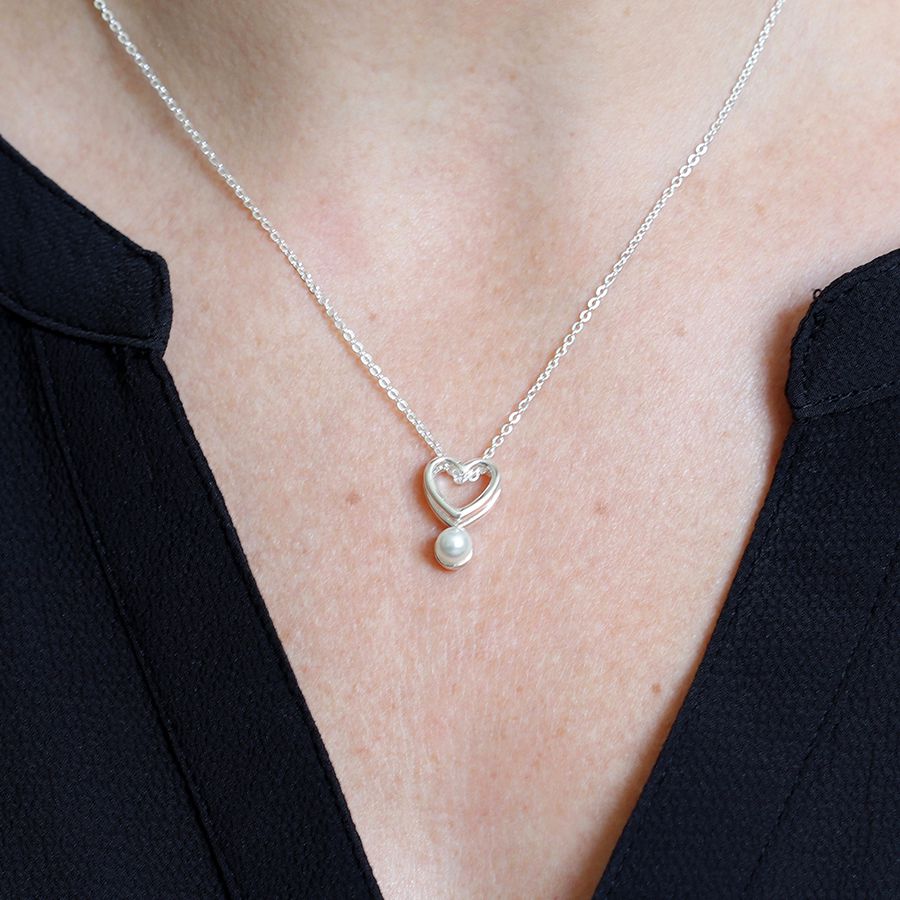 Fine chain silver plated necklace with a double layer open heart and a single white faux pearl worn close up
