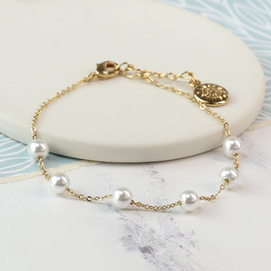 Delicate gold plated bracelet embellished with white glass pearls.