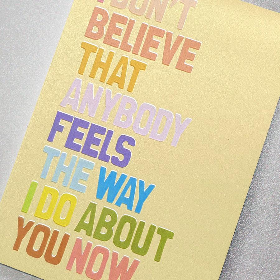 A gorgeous golden glitter effect greeting card with rainbow lettering featuring the slogan: I don't believe that anybody feels the way I do about you now